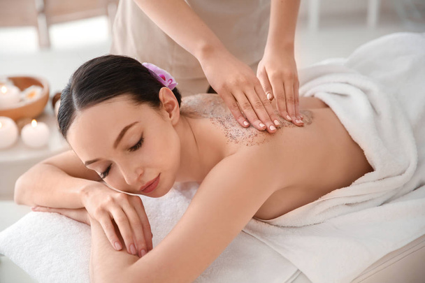 Beautiful young woman having massage with body scrub in spa salon - Zdjęcie, obraz