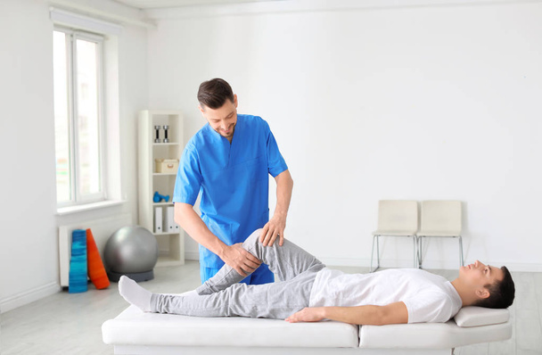 Fysiotherapeut werkt met mannelijke patiënt in kliniek - Foto, afbeelding