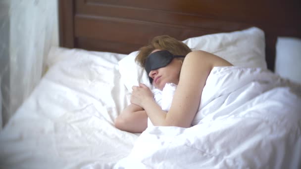 Young woman in a mask for sleeping, sleeping in bed on a pillow in the daytime. 4k. - Video