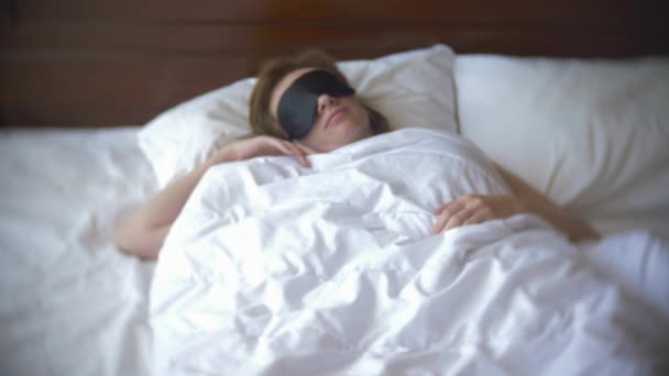 Young woman in a mask for sleeping, sleeping in bed on a pillow in the daytime. 4k. - Πλάνα, βίντεο