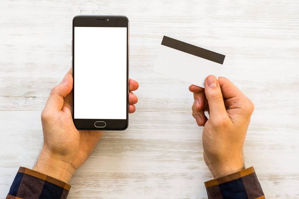 makieta smartphone i karty kredytowej w ręce zbliżenie zdjęcie biznesmen posiadania karty kredytowej ręcznie i za pomocą smartfonu. Płatności online plastikowej karty. Makieta poziome. Niewyraźne - Zdjęcie, obraz