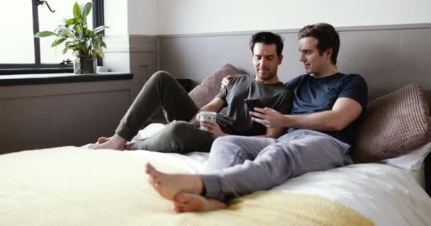 Young male couple looking at smartphone together - Footage, Video