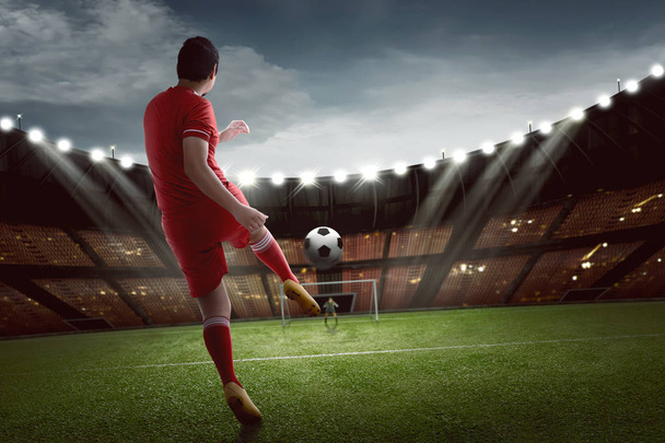 Attractive asian football player shooting the ball to goal at match - Foto, imagen