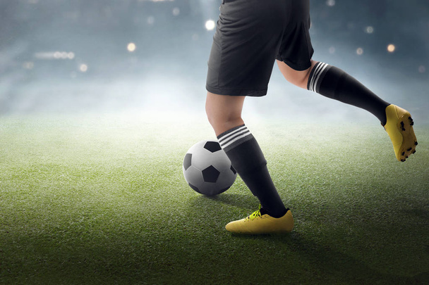 Soccer player trying to kicking the ball on the grass field - Foto, imagen