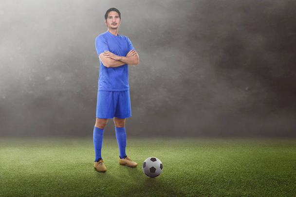 Handsome asian football player with crossed arms on the grass field - Foto, imagen