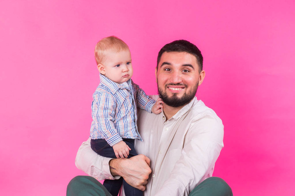 Gelukkig portret van de vader en zoon op roze achtergrond. In studio - Foto, afbeelding