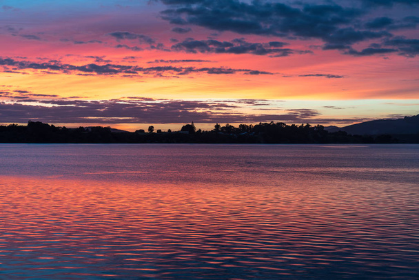 Intense sunrise reflects red on water - Photo, Image