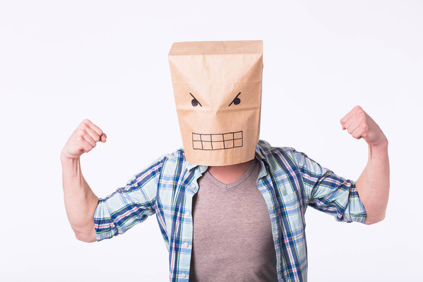 Hombre con caja de cartón en la cabeza y dibujo de cara de emoticono enojado. Hombre enojado comenzando una pelea
. - Foto, Imagen