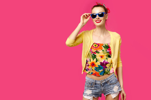 Young beautiful girl in a yellow sweater and sunglasses on a pink background laughing. Colour obsession concept.  Minimalistic style. Stylish Trendy - Photo, Image