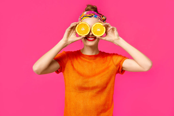 Jeune femme sur fond rose tient une coupe orange dans ses mains et rit. Concept d'obsession des couleurs. Style minimaliste. Tendance élégante
 - Photo, image