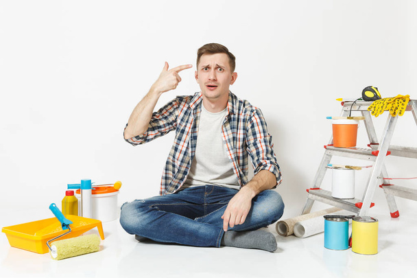 Confused shocked man point fingers to head as if he about shoot himself. Instruments for renovation apartment isolated on white background. Wallpaper, gluing accessories, tools. Repair home concept. - Photo, Image