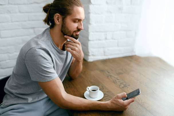 Young Man Drinking Coffee And Using Phone - Φωτογραφία, εικόνα