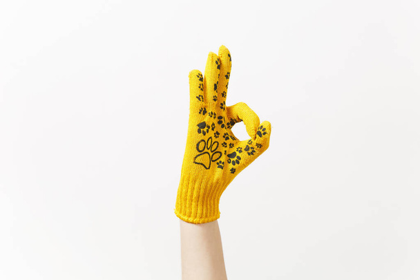 Primer plano de la mano femenina en la construcción de guantes amarillos que muestran gesto OK aislado sobre fondo blanco. Accesorios, herramientas para la renovación de la habitación del apartamento. Reparar concepto de casa. Copiar espacio para publicidad
. - Foto, imagen