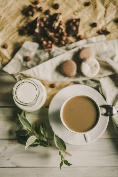 Macarons vícebarevné a poháry s černou kávu a na dřevěný stůl s různými přísadami, čokoláda, káva, mandarinky a další. Pohled shora. - Fotografie, Obrázek
