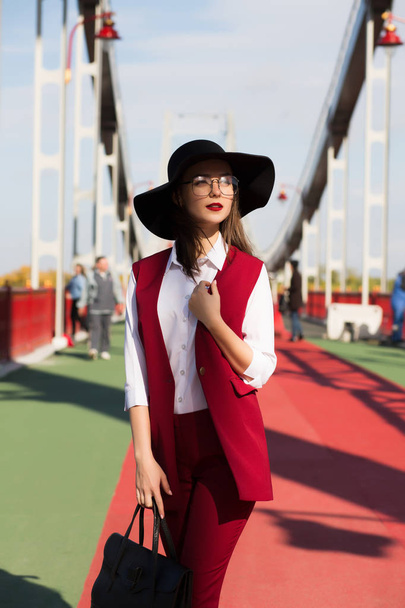 Modne ubrana Dziewczyna Brunetka w czerwonym pantsuit i czarny kapelusz  - Zdjęcie, obraz