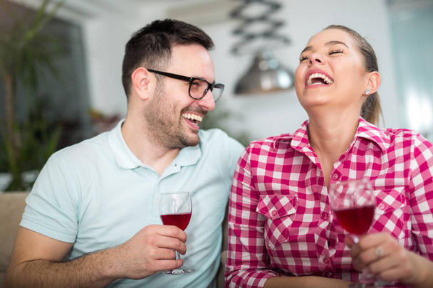 Photo of a young cheerful couple toasting at home with wine. - Foto, immagini