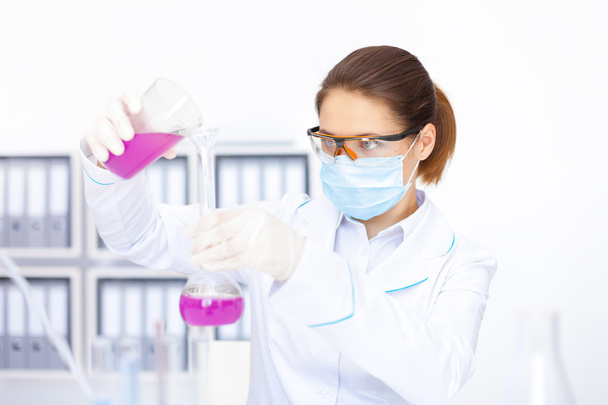 Young female researcher pouring chemicals - Fotó, kép