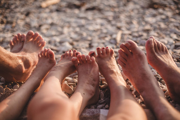 family of four resting on the beach. Legs - Zdjęcie, obraz