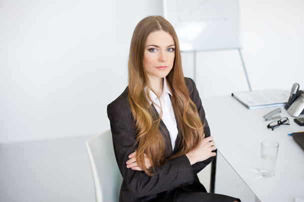 Portrait of beautiful young business woman sitting at desk at of - Фото, изображение