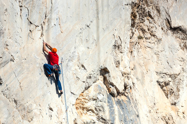 Un hombre está entrenando para trepar sobre una roca
. - Foto, imagen