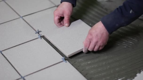 Master puts and glues tile floor tiles. Laying of tile adhesive. - Video, Çekim