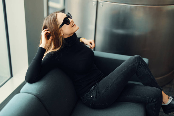 Young pretty girl sit on the sofa wear glasses and smile to came - Фото, зображення