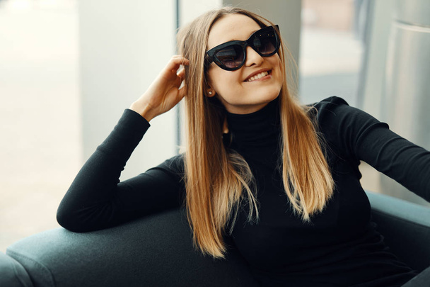 Young pretty girl sit on the sofa wear glasses and smile to came - Фото, зображення