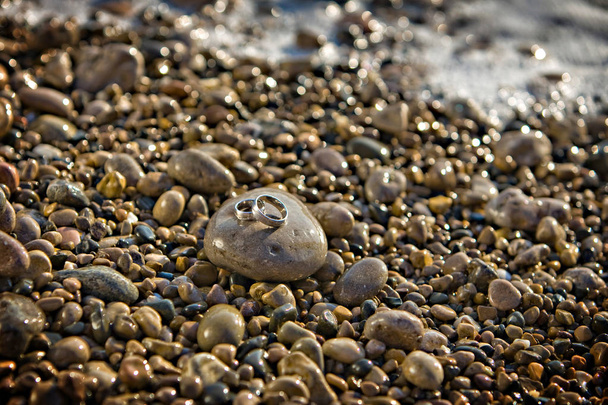 vihkisormukset makaavat meren rannalla kivi
 - Valokuva, kuva