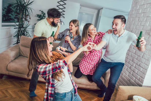 Группа друзей, играющих в караоке дома. Концепция о дружбе, домашних развлечениях и людях - Фото, изображение