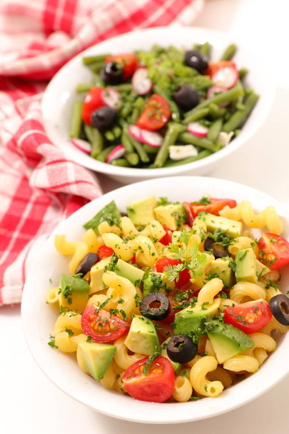 delicious pasta salad and bean salad in plates on kitchen table - Photo, image