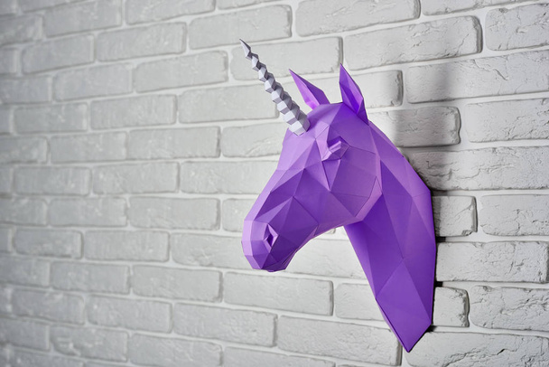 Bright violet unicorn hanging on the wall. - 写真・画像