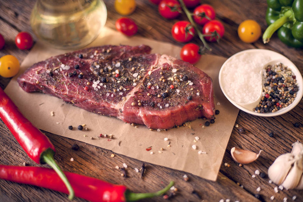 Rauw vlees biefstuk van rundvlees op donkere houten achtergrond, afgezwakt - Foto, afbeelding