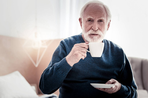 Pleasant elderly man holding a cup of tea - Fotoğraf, Görsel