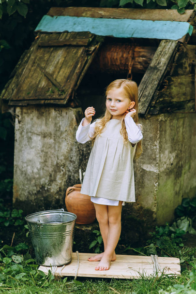 cute little girl with white hair at the well outdoors - Foto, Imagem