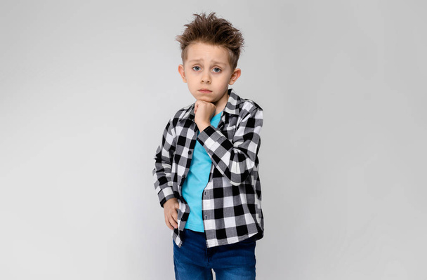 Niño preescolar caucásico agradable en traje casual que muestra diferentes expresiones en la pared blanca en el estudio
.  - Foto, imagen