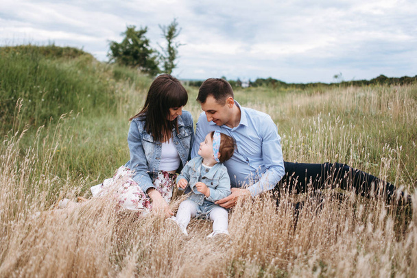 Vue de face de la jeune famille assise sur un champ de blé par temps gris
 - Photo, image