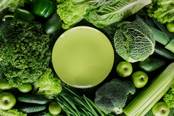 top view of green plate between green vegetables, healthy eating concept - Fotografie, Obrázek