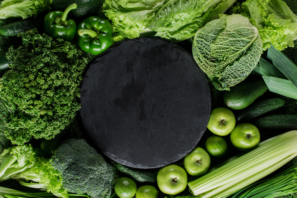 top view of black cutting board between green vegetables, healthy eating concept - Fotografie, Obrázek