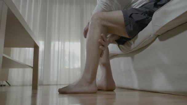 Senior man doing himself massage therapy on his tired legs relieve the pain and stress at home - Materiał filmowy, wideo