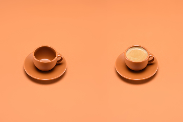 close up view of empty cup and cup of coffee isolated on peach - Fotó, kép
