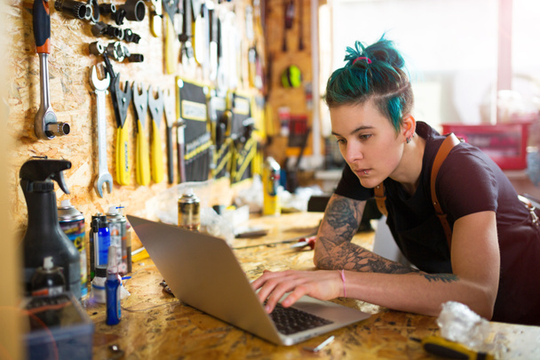 Жінка використовує ноутбук у майстерні по ремонту велосипедів
 - Фото, зображення