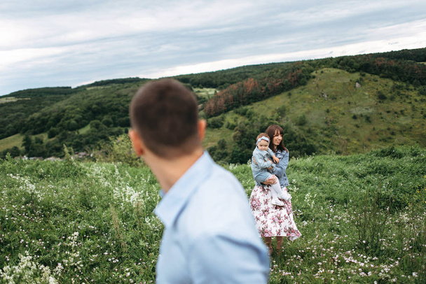 Nuori perhe kävelee yhdessä pellolla
 - Valokuva, kuva