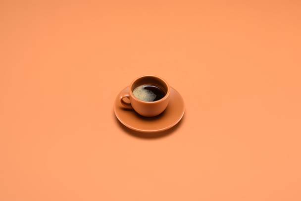 close up view of cup of coffee on saucer isolated on peach - Фото, зображення