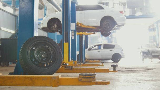The tire in front of a service station with cars on the lift - Photo, Image