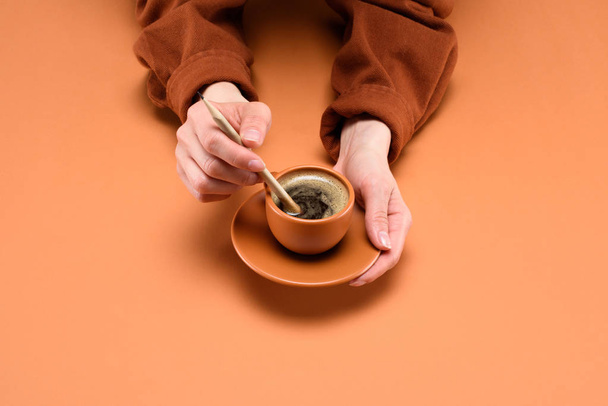 partial view of female hands with cup of coffee and pencil isolated on peach - Fotó, kép