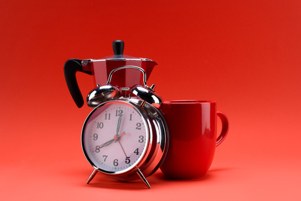 lähikuva kahvinkeitin, herätyskello ja kuppi kahvia eristetty punaisella
 - Valokuva, kuva
