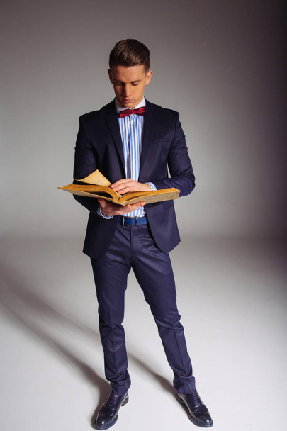 a man, a guy in a blue suit, stands and reads an old book, the concept of knowledge, study, science, business, everything new, it's a well-forgotten old - Foto, Bild