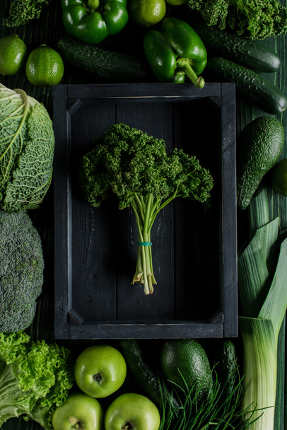 κάτοψη του μάτσο μαϊντανό σε ξύλινο κουτί ανάμεσα τα πράσινα λαχανικά, υγιεινό φαγητό έννοια - Φωτογραφία, εικόνα