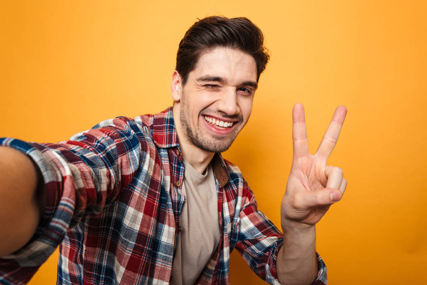 Portrait of a cheerful young man taking a selfie - 写真・画像
