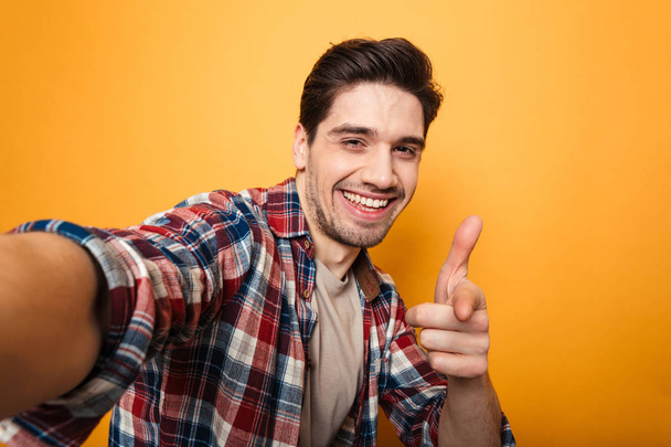 Portrait of a cheerful young man taking a selfie - Fotó, kép